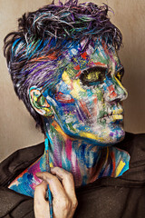 Close up studio portrait of man with colorful face painting. Emotional beautiful guy. 