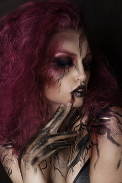 Close up portrait of sexy beautiful witch with Halloween makeup. Beautiful flying pink hair. Professional creative face painting	
