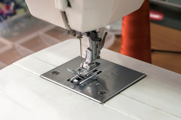 Needle and foot of sewing machine closeup as manufactoring background