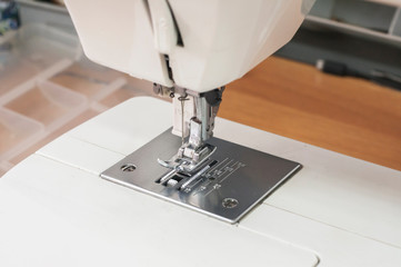 Needle and foot of sewing machine closeup as manufactoring background