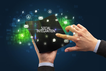 Businessman holding a foldable smartphone with SOCIAL INTEGRATION inscription, social networking concept