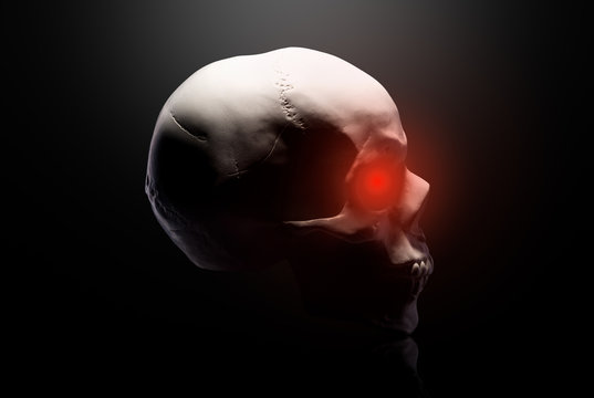 Model of the human skull with red eyes isolated on black background