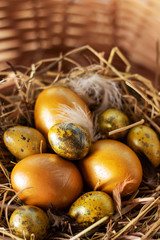 Easter composition. Cute painted easter eggs  are placed on nice haystack from dried straws and inside wicker basket. Greeting card concept.