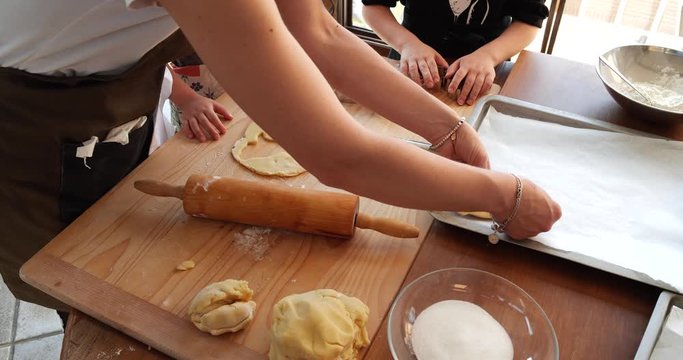 Young mother cooking biscuits with her two kids, mixing flour with eggs, sugar, butter, lemon