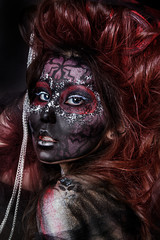 close up portrait of terribly beautiful girl with Halloween skull makeup. Black face painting. lush hair