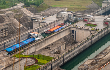 Three Gorges Dam, China - May 6, 2010: Yangtze River. Foggy morning, Lower sections of adjacent ship lifts. Beige concrete and black dirt. Green garden in between. Blue, orange barges in locks.