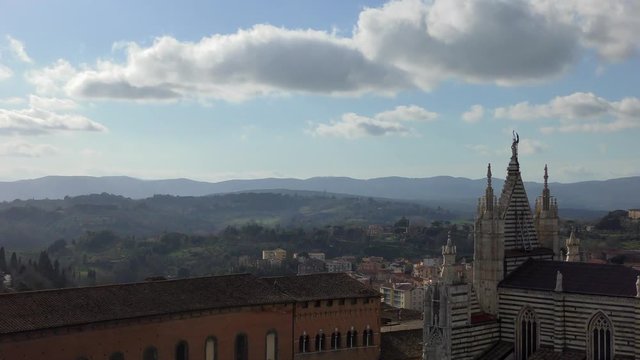 A view from the heights of the Cathedral of ancient Siena against the backdrop of the hills under a beautiful cloudy sky. Tuscany, Italy.
