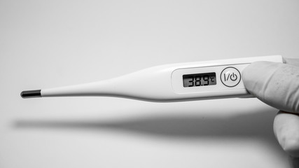hands holding white digital thermometer on white background. Showed 38.9 c’. Fever and healthcare...