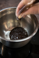 Hands pouring chocolate to the metal bowl