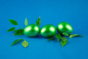 green painted eggs and branches with leaves, Easter mood, concept of natural organic healthy products