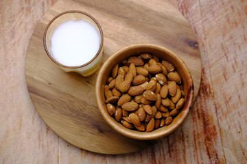 raw almond and glass of milk on wooden table.