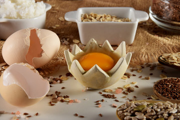 raw egg yolk accompanied by various seeds and egg shells