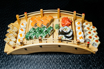 Sushi set on a wooden bridge on a black table