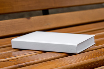 White book without images lies on a wooden bench