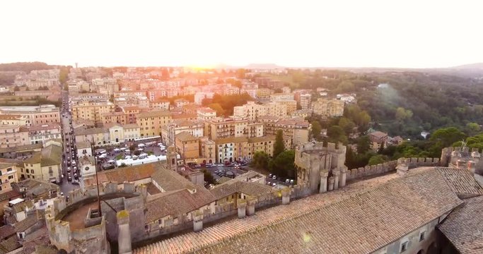 Aerial, drone shot over the Castello Odescalchi fortress towards the Bracciano town, during sunset, in Lazio, Italy