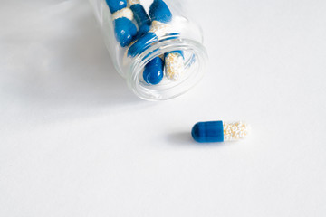 blue capsule pills in glass bottle on white background. drugs isolated white copy space. healthcare medicine concept, aspirin, antibiotics