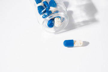 blue capsule pills in glass bottle on white background. drugs isolated white copy space. healthcare medicine concept, aspirin, antibiotics