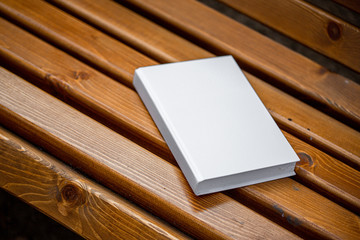 White book without images lies on a wooden bench