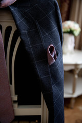 A man's wedding suit with a boutonniere hangs on the back of a chair.