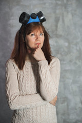 Young woman with respirator thinks about epidemic on grey background. Isolation and virus...