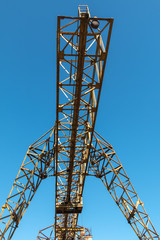 Vintage working gantry crane rusty yellow, bottom view, close-up against a blue spring sky