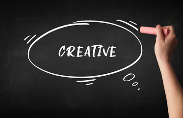 Hand drawing CREATIVE inscription with white chalk on blackboard, education concept