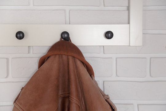 Brown leather jacket hanged on white wall hanger