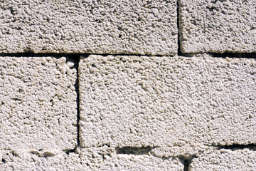Light grey brick wall background, texture of limestone. Straight symmetric lines between bricks.