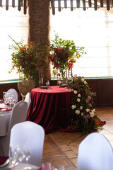 round table with a red tablecloth surrounded by floral arrangements