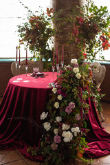 round table with a red tablecloth surrounded by floral arrangements