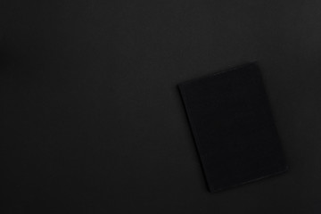 A hardcover black book on a black background. Copy space. Dark mode style. Top view. Minimal concept