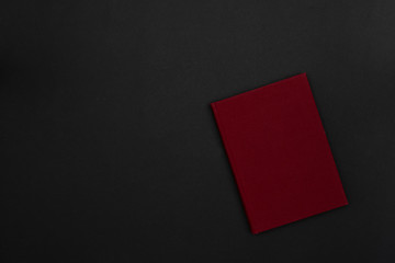 A hardcover red book on a black background. Copy space. Dark mode style. Top view. Minimal concept