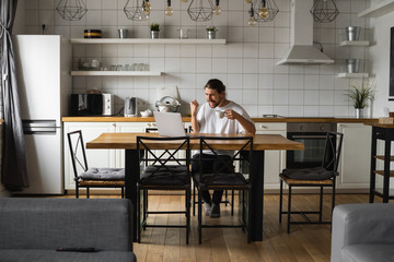 Young freelancer succeed with project working from home. Excited glad young freelancer triumphing...