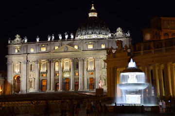 Fototapeta na wymiar Night view of the illuminated fountains in St. Peter's Square with the basilica in the background. Travel concept