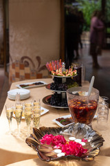 fruit bowl with fig slices, white and black grapes, a glass with lollipops, a plate with sliced smoked meats, a plate with slices of cheese, glasses with champagne, a bowl with punch