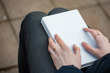 A girl holds a white book in her hands.