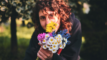 Obraz premium Beautiful happy girl pose with a colorful bouquet of fresh collected spring flowers