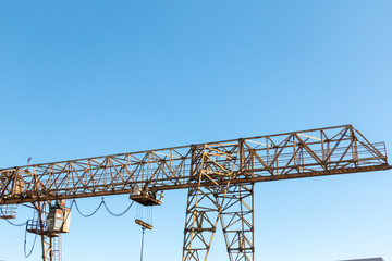 Vintage working gantry crane rusty yellow, bottom view, close-up against a blue spring sky