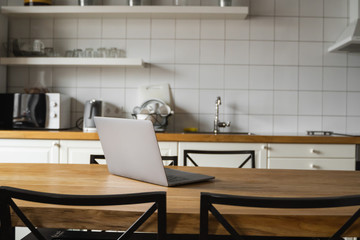 Close Up of laptop on kitchen counter with kitchen on background.