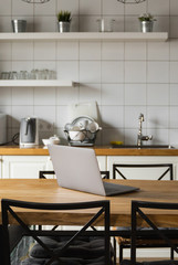 Close Up of laptop on kitchen counter with kitchen on background.