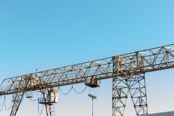 Vintage working gantry crane rusty yellow, bottom view, close-up against a blue spring sky