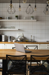 Close Up of laptop on kitchen counter with kitchen on background.