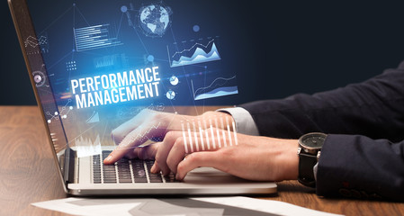Businessman working on laptop with PERFORMANCE MANAGEMENT inscription, new business concept