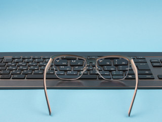 Glasses and keyboard on a blue background.