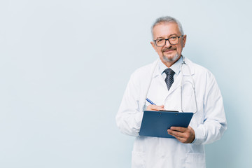 Elderly bearded male doctor in white uniform with a stethoscope with a blue folder. Doctor on the background of a medical research laboratory.