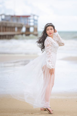 Fototapeta na wymiar Beautiful woman in white dress happily strolling at the beach, beautiful woman dressed in white bride