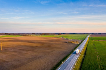 Aerial view of a highway passing through spring agricultural fields at sunset