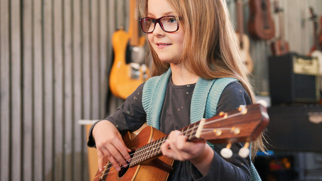 Dad Teaching Guitar And Ukulele To His Daughter.Little Girl Learning Guitar At Home.Close Up.Ukulele Class At Home. Child Learning Guitar From Her Father