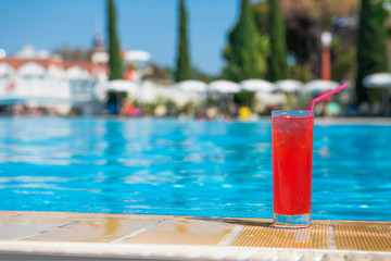 Fototapeta na wymiar Refreshing cocktails Cosmopolitan stand on the edge of the pool in the summer heat with a blurred background. The concept of rest and travel is an expensive holiday. place for text.