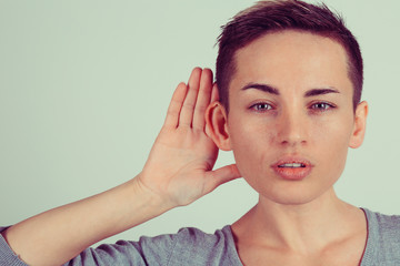 Closeup portrait young nosy woman hand to ear gesture carefully intently secretly listening juicy...